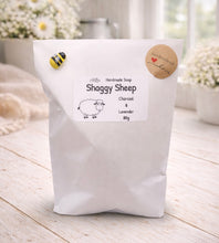 Load image into Gallery viewer, White bag of Shaggy Sheep handmade soap with a label on a light wooden surface.
