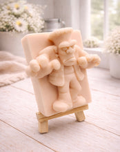 Load image into Gallery viewer, A rectangular handmade vegan soap featuring a high-relief carving of Frankenstein's monster in a classic pose with arms outstretched and a grumpy expression, displayed on a miniature wooden easel.
