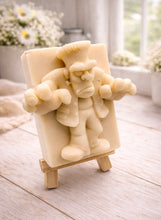 Load image into Gallery viewer, A rectangular handmade vegan soap featuring a high-relief carving of Frankenstein's monster in a classic pose with arms outstretched and a grumpy expression, displayed on a miniature wooden easel.
