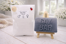 Load image into Gallery viewer, A rectangular handmade vegan soap featuring the words "GAY BAR" in large, bold, 3D block lettering, displayed on a miniature wooden easel.
