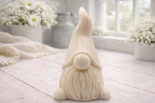 Load image into Gallery viewer, A handmade vegan soap sculpted in the shape of a charming gnome (or gonk), featuring a tall, pointed hat pulled down over the eyes and a full, textured beard, in a natural cream colour.
