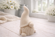 Load image into Gallery viewer, A handmade vegan soap sculpted in the shape of a charming gnome (or gonk), featuring a tall, pointed hat pulled down over the eyes and a full, textured beard, in a natural cream colour.
