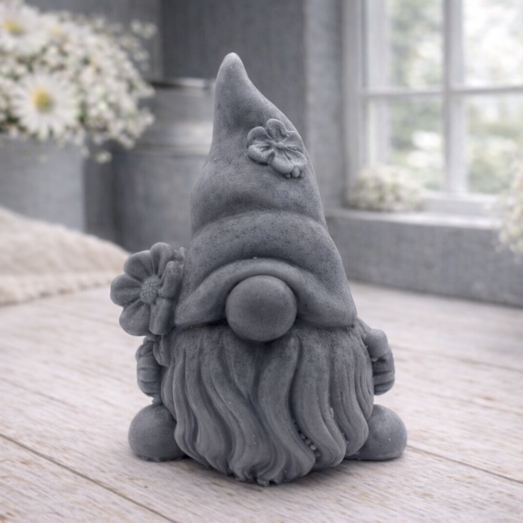 A 3D handmade vegan soap in a warm cream tone, sculpted into a cute garden gnome or gonk with a long flowing beard, a large round nose, and a tall pointed hat adorned with small embossed flowers.