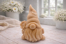 Load image into Gallery viewer, A 3D handmade vegan soap in a warm cream tone, sculpted into a cute garden gnome or gonk with a long flowing beard, a large round nose, and a tall pointed hat adorned with small embossed flowers.
