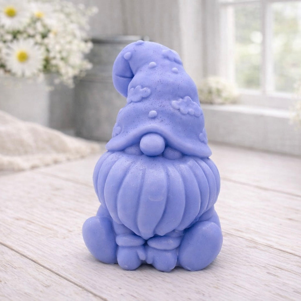 A handmade vegan soap in a natural tone, sculpted as a gnome (gonk) with a tall, curved hat that covers the eyes and has clouds on it, a round nose, and a long, textured beard.