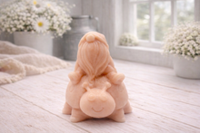 Load image into Gallery viewer, A handmade vegan soap in a warm terracotta-peach tone, sculpted as a whimsical gnome (gonk) with a long, flowing beard sitting on the back of a large, smiling ladybird with visible spots, displayed on a light wooden surface.
