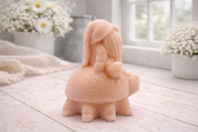Load image into Gallery viewer, A handmade vegan soap in a warm terracotta-peach tone, sculpted as a whimsical gnome (gonk) with a long, flowing beard sitting on the back of a large, smiling ladybird with visible spots, displayed on a light wooden surface.
