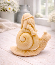 Load image into Gallery viewer, A handmade vegan soap gift, sculpted as a whimsical gnome (gonk) with a tall, slouchy hat and a long beard, sitting on the shell of a large snail with a textured, bumpy body.
