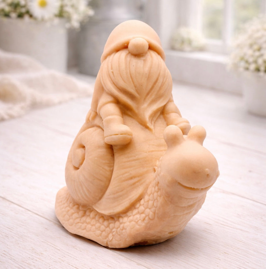 A handmade vegan soap gift, sculpted as a whimsical gnome (gonk) with a tall, slouchy hat and a long beard, sitting on the shell of a large snail with a textured, bumpy body.