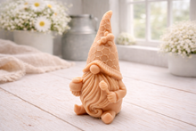 Load image into Gallery viewer, A handmade vegan soap in the shape of a gnome with a long beard, wearing a honeycomb-patterned hat with a bee, holding a honey pot and dipper.
