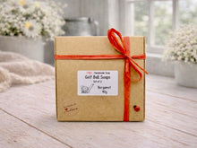 Load image into Gallery viewer, Box of handmade vegan golf ball soaps with a red ribbon on a wooden surface
