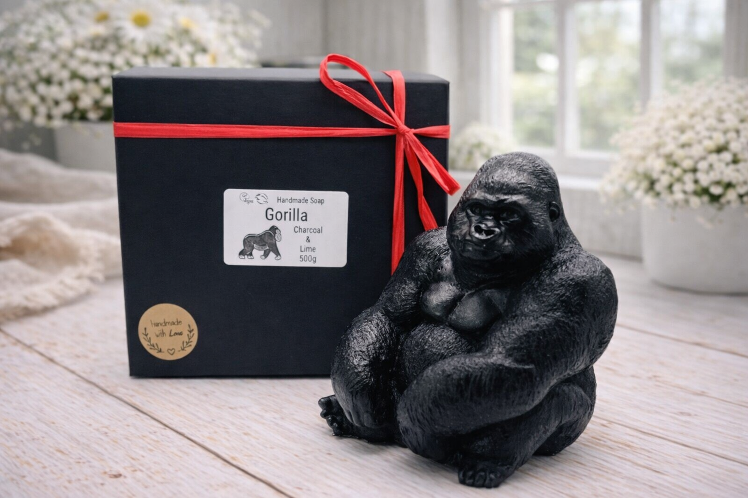 A highly detailed handmade vegan soap in a natural colour, sculpted in the shape of a sitting gorilla with realistic fur and muscle textures, displayed on a light wooden surface. Gift boxed. 
