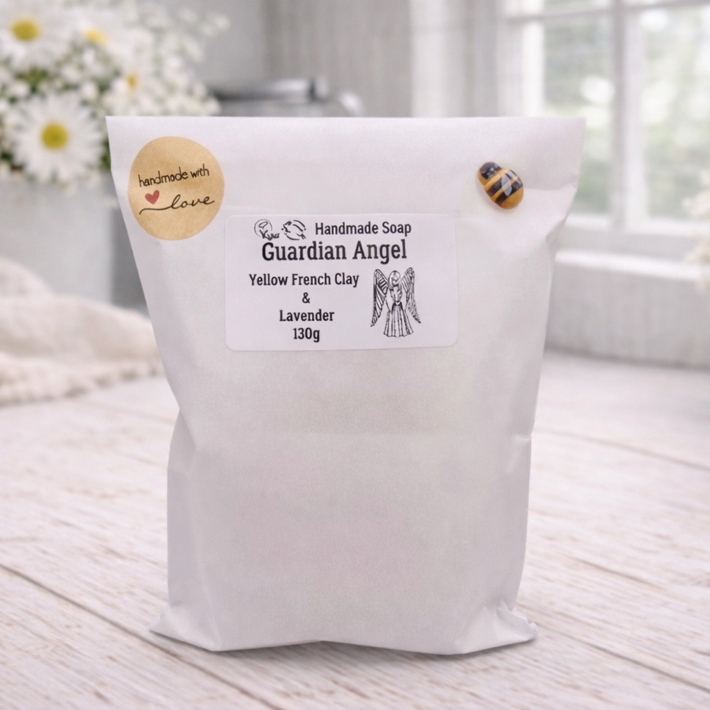 Handmade soap packaging labeled 'Guardian Angel' on a wooden surface with flowers in the background.