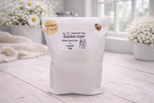 Load image into Gallery viewer, Handmade soap packaging labeled 'Guardian Angel' on a wooden surface with flowers in the background.

