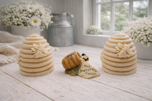 Load image into Gallery viewer, Two handmade vegan soaps sculpted into traditional dome-shaped beehives (skeps) with small bees resting on the sides, flanking a decorative centrepiece featuring a honey pot and the words "The Sweetest Thing," all displayed on a rustic wooden surface.
