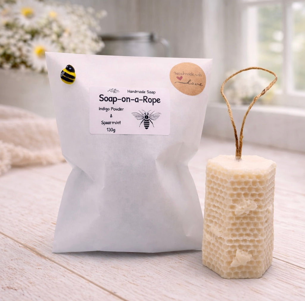 A tall, rectangular handmade vegan soap with a detailed honeycomb texture on all sides and small embossed bees, featuring a natural twine hanging rope, displayed upright on a light wooden surface.