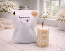 Load image into Gallery viewer, A tall, rectangular handmade vegan soap with a detailed honeycomb texture on all sides and small embossed bees, featuring a natural twine hanging rope, displayed upright on a light wooden surface.
