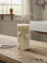 Load image into Gallery viewer, A tall, rectangular handmade vegan soap with a detailed honeycomb texture on all sides and small embossed bees, featuring a natural twine hanging rope, displayed upright on a light wooden surface.
