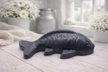 Load image into Gallery viewer, Handmade vegan soap sculpted in the shape of a koi carp fish with detailed scales and fins, resting on a light timber surface with a soft floral background.
