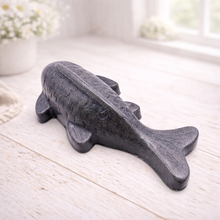 Load image into Gallery viewer, Handmade vegan soap sculpted in the shape of a koi carp fish with detailed scales and fins, resting on a light timber surface with a soft floral background.
