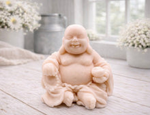 Load image into Gallery viewer, A 3D handmade vegan soap sculpted into a joyful Laughing Buddha sitting in a meditative pose, holding prayer beads and a small bowl, displayed in a bright farmhouse setting
