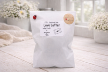 Load image into Gallery viewer, White bag of 'Love Letter' soap with decorative elements on a light wooden surface.
