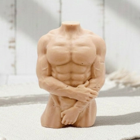 A highly detailed handmade vegan soap in the shape of a muscular male torso, featuring a detailed sculptural design, displayed against a whimsical background for a sophisticated farmhouse decor touch.