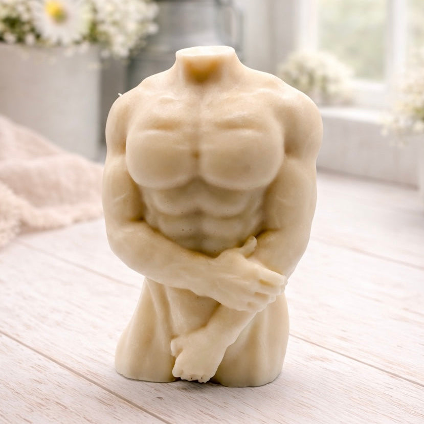 A 3D handmade vegan soap sculpted into a detailed male torso with defined chest and abdominal muscles, finished in a soft tone and displayed in a bright farmhouse setting.
