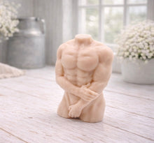 Load image into Gallery viewer, A 3D handmade vegan soap sculpted into a detailed male torso with defined chest and abdominal muscles, finished in a soft tone and displayed in a bright farmhouse setting.
