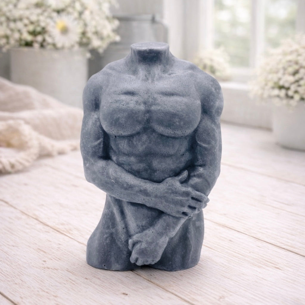 A 3D handmade vegan soap sculpted into a detailed male torso with defined chest and abdominal muscles, finished in a soft tone and displayed in a bright farmhouse setting.
