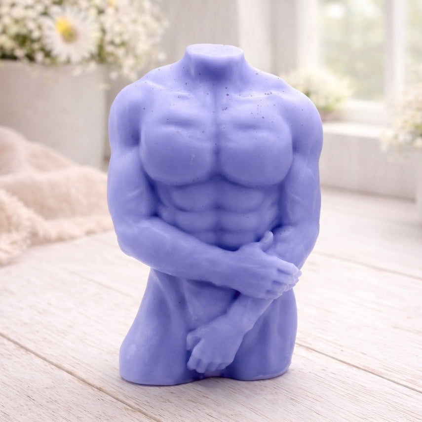 A 3D handmade vegan soap sculpted into a detailed male torso with defined chest and abdominal muscles, finished in a soft tone and displayed in a bright farmhouse setting.
