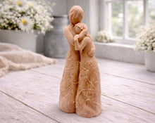 Load image into Gallery viewer, A 3D handmade vegan soap, sculpted as a mother and daughter in a tender standing embrace, featuring an intricate embossed floral and vine pattern on their dresses.
