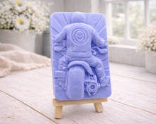 Load image into Gallery viewer, detailed handmade vegan soap gift featuring a motorcycle rider with a skull emblem on their jacket, displayed on a wooden easel against a whimsical farmhouse decor background
