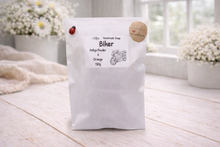 Load image into Gallery viewer, White soap bag with 'Biker'  with a label on a light wooden surface.
