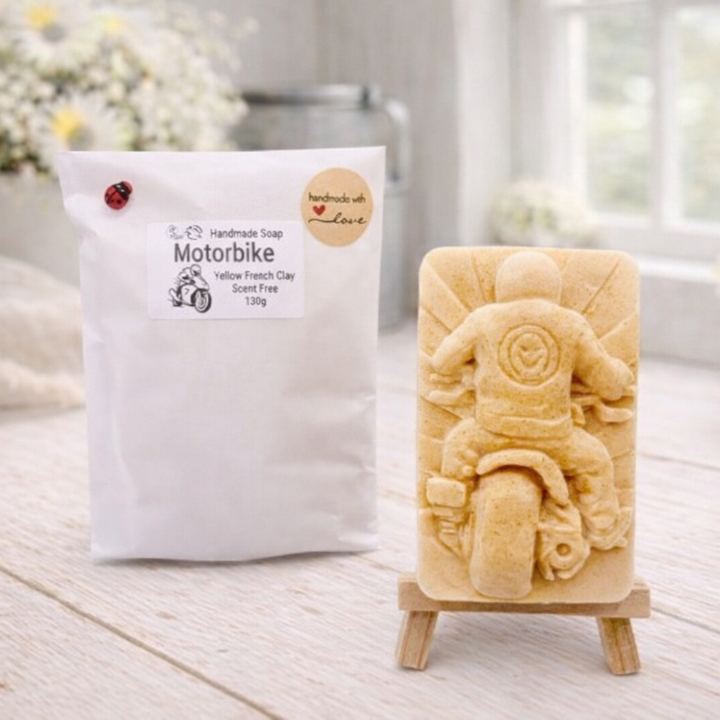 Handmade soap shaped like a motorcycle on a stand with packaging labeled 'Motorbike' in a bright setting.