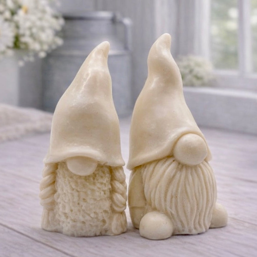 A pair of handmade vegan soaps, featuring a Mr and Mrs Gnome (gonk) set; one with a full textured beard and the other with thick braided plaits, both wearing tall, pointed hats. Gift boxed. 