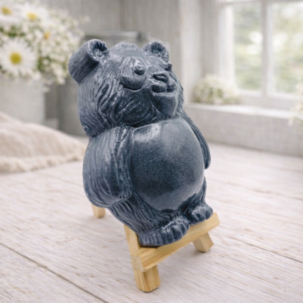 Handmade vegan soap sculpted in the shape of a round, sitting panda bear with detailed fur textures and a friendly expression, displayed on a small wooden easel.