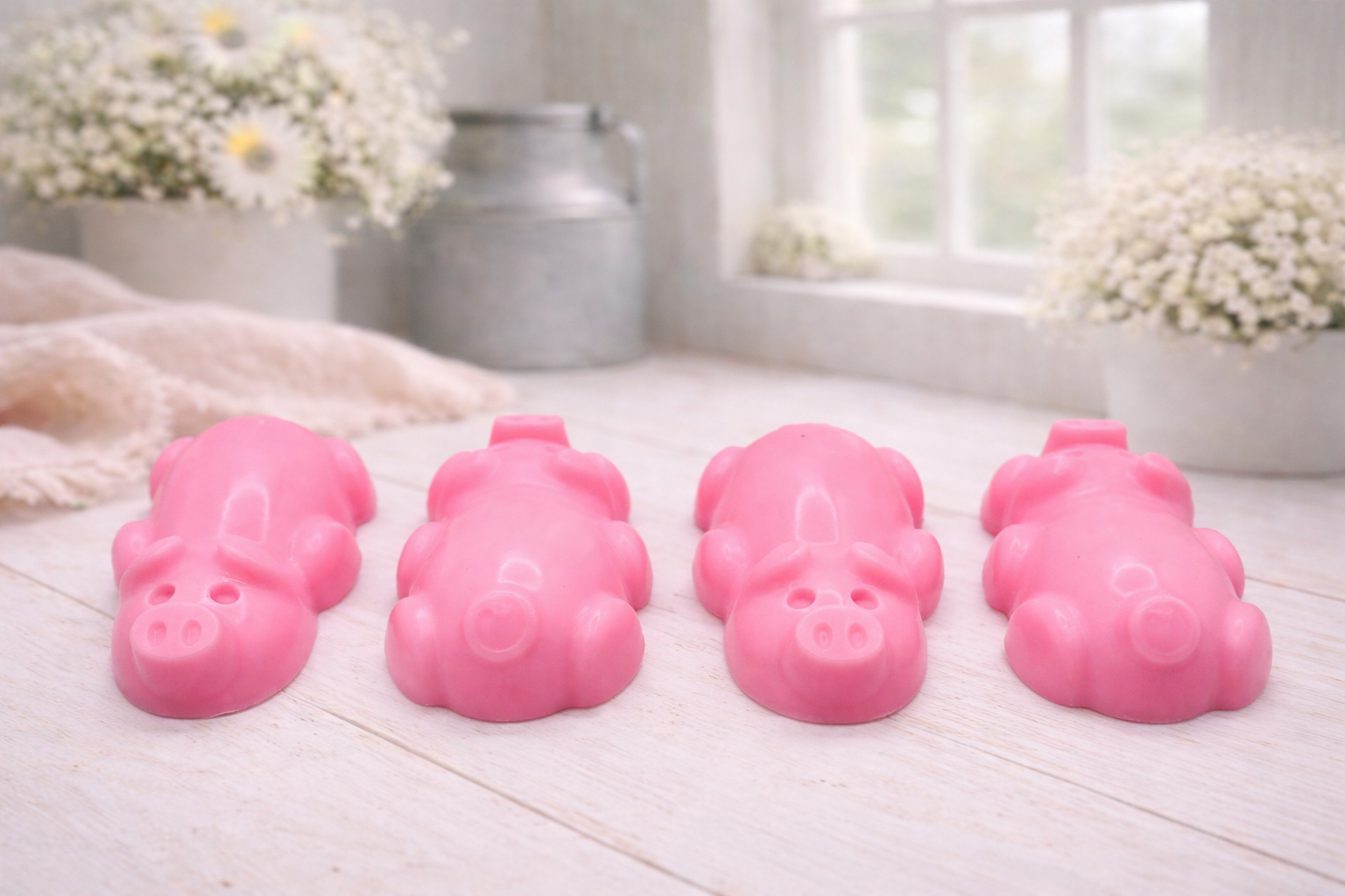 A charming collection of four handmade vegan soaps featuring four piglets, each intricately sculpted with realistic textures and playful expressions, arranged on a light wooden surface.
