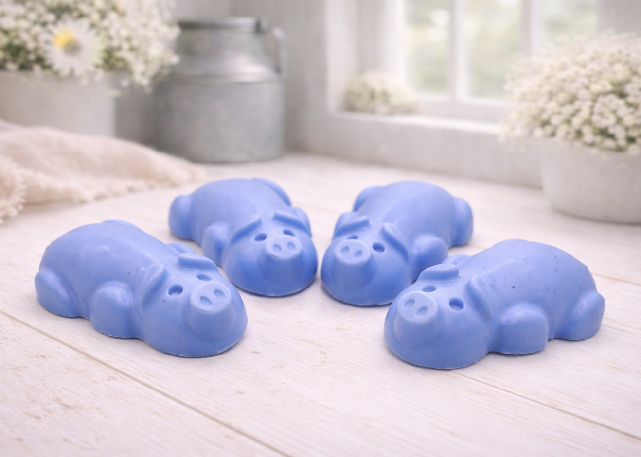 A charming collection of four handmade vegan soaps featuring four piglets, each intricately sculpted with realistic textures and playful expressions, arranged on a light wooden surface.