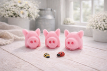 Load image into Gallery viewer, A set of three handmade vegan soaps sculpted into cute pigs with round snouts and floppy ears, displayed with a small decorative bee and ladybird on a white wooden surface.
