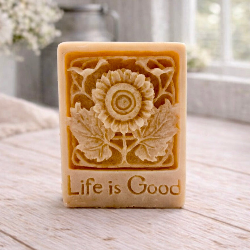 Bar of soap with floral design and 'Life is Good' text on a wooden surface.