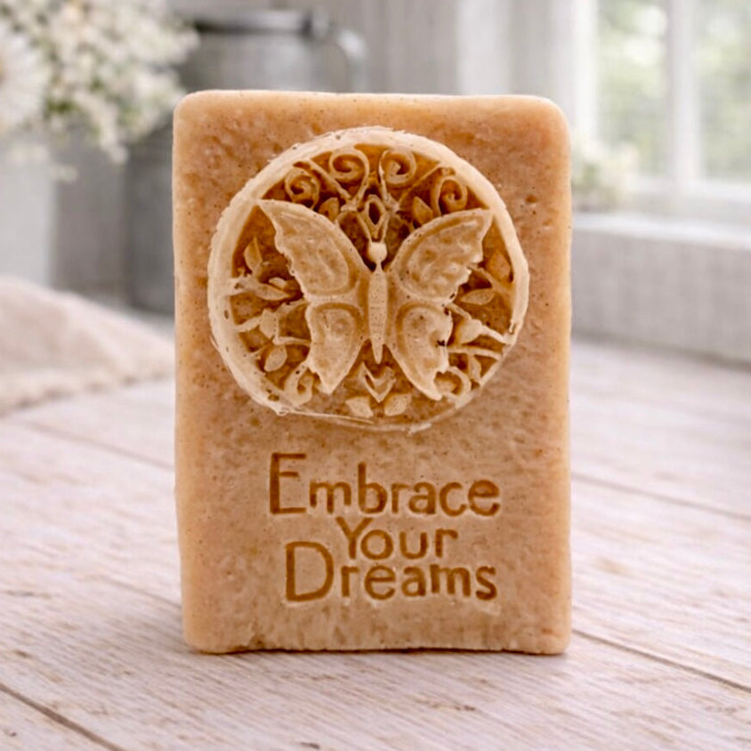 Bar of soap with butterfly design and 'Embrace Your Dreams' text on a wooden surface.
