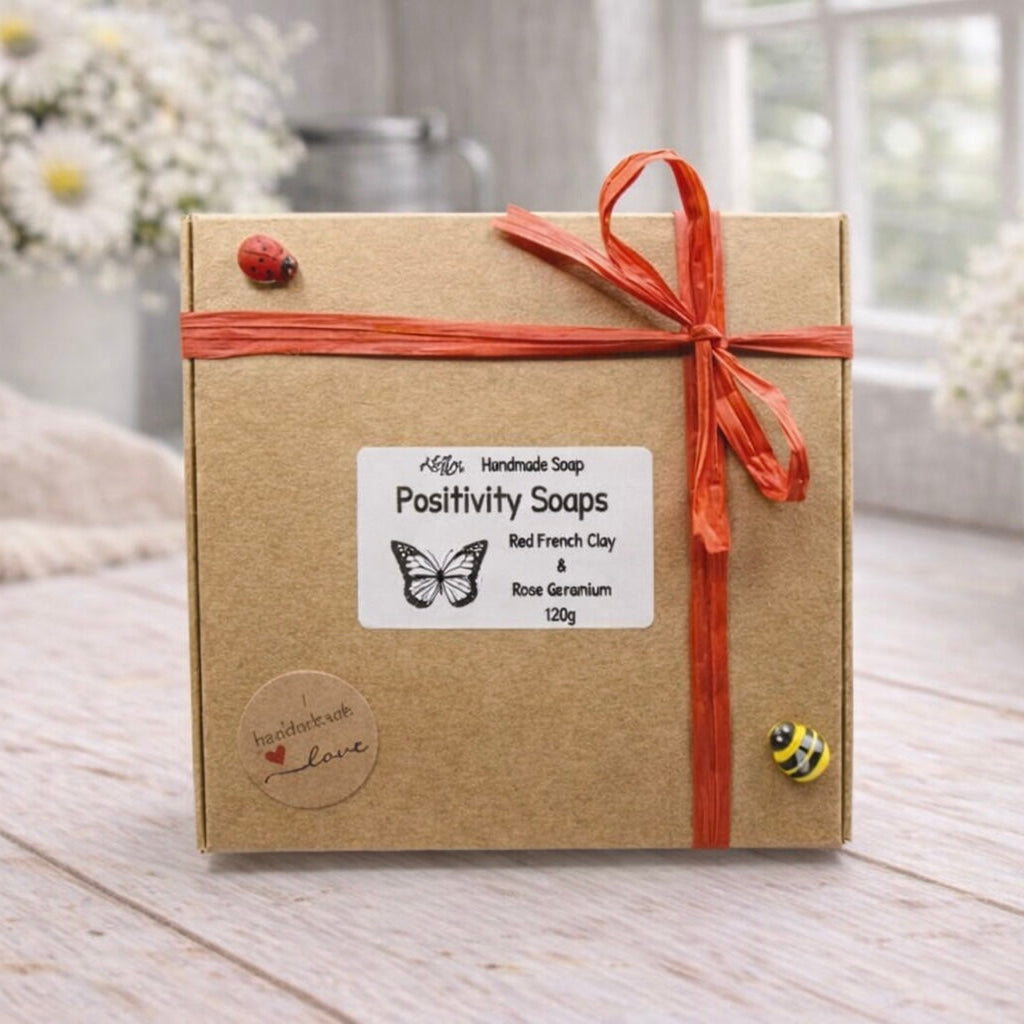 Box of Positivity Soaps with a red ribbon on a wooden surface