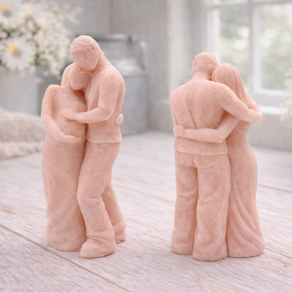 A 3D handmade vegan soap in a warm cream tone, sculpted into a standing figure of a pregnant couple; the partner stands behind the expectant mother, tenderly cradling her baby bump, displayed on a light wooden surface in a bright farmhouse setting.