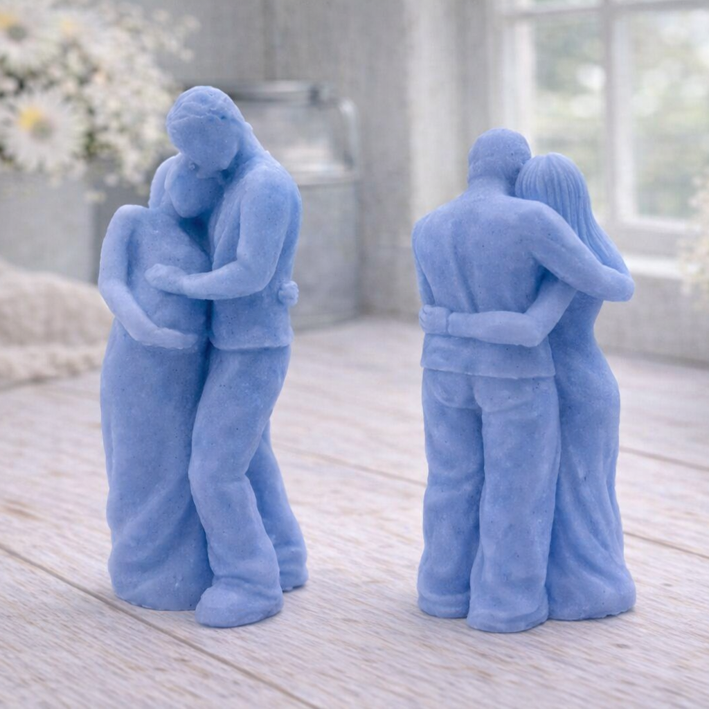 A 3D handmade vegan soap in a warm cream tone, sculpted into a standing figure of a pregnant couple; the partner stands behind the expectant mother, tenderly cradling her baby bump, displayed on a light wooden surface in a bright farmhouse setting.