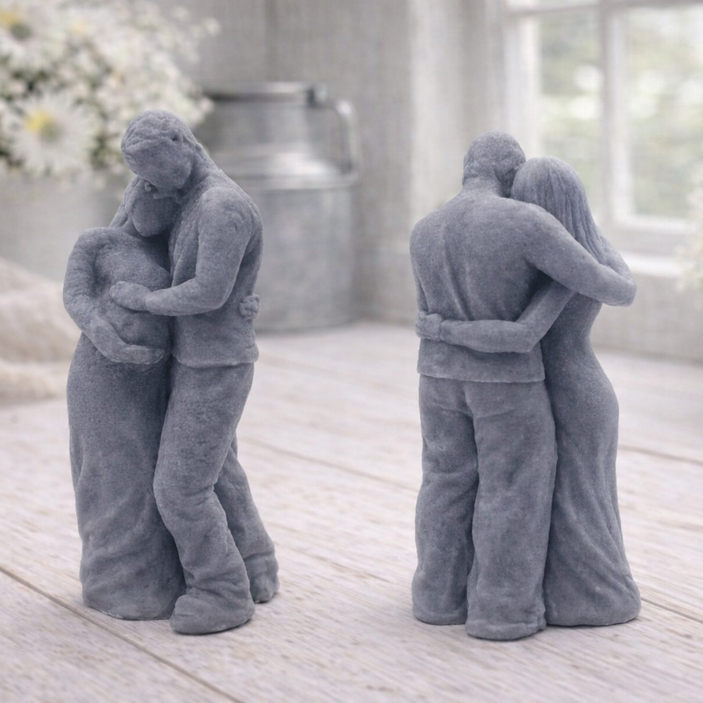 A 3D handmade vegan soap in a warm cream tone, sculpted into a standing figure of a pregnant couple; the partner stands behind the expectant mother, tenderly cradling her baby bump, displayed on a light wooden surface in a bright farmhouse setting.