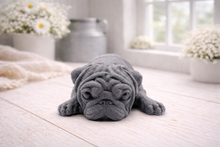 Load image into Gallery viewer, A detailed handmade vegan soap gift, sculpted in the shape of a pug dog lying flat on its stomach in a sleeping position, showing realistic skin folds and fur texture, displayed on a light wooden surface. Handmade in Blackpool 
