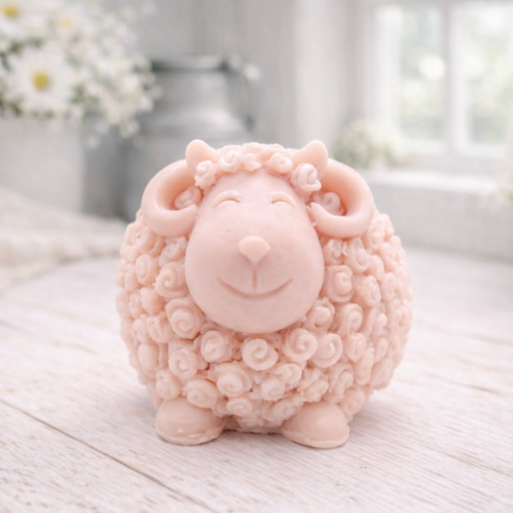 A highly detailed handmade vegan soap sculpted in the shape of a sturdy ram with a thick coat of tight, curly wool and large, elegant curved horns, displayed on a light wooden surface in a bright farmhouse setting.