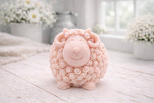 Load image into Gallery viewer, A highly detailed handmade vegan soap sculpted in the shape of a sturdy ram with a thick coat of tight, curly wool and large, elegant curved horns, displayed on a light wooden surface in a bright farmhouse setting.
