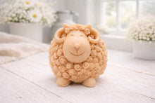 Load image into Gallery viewer, A highly detailed handmade vegan soap sculpted in the shape of a sturdy ram with a thick coat of tight, curly wool and large, elegant curved horns, displayed on a light wooden surface in a bright farmhouse setting.
